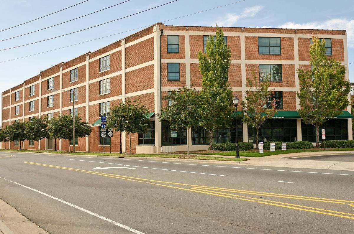 Long three-storey brick warehouse building running along a wide empty road, with green awnings over ground-floor windows.