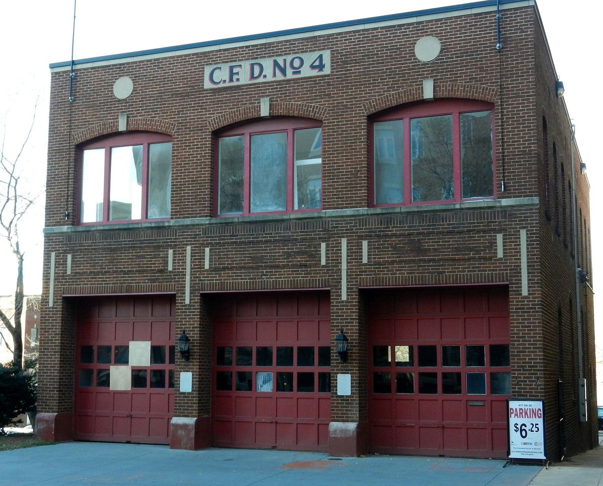 Two-storey brick fire station with three arched red engine-bay doors and the lettering C.F.D. No 4 across the parapet.